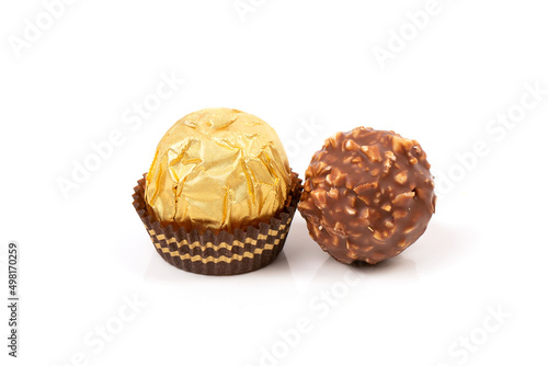 A round candy in a gold package and an unwrapped candy poured with chocolate and waffle crumbs.