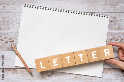 「LETTER」と書かれた積み木、ノート、ペン、手