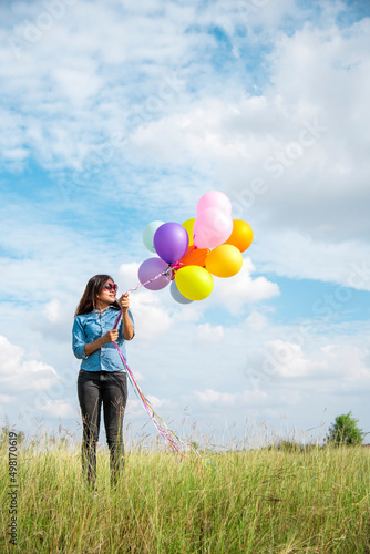 Woman holding balloons running on green meadow white cloud and blue sky with happiness Cheerful and relax. Hands holding vibrant air balloons play on birthday party happy times summer sunlight outdoor