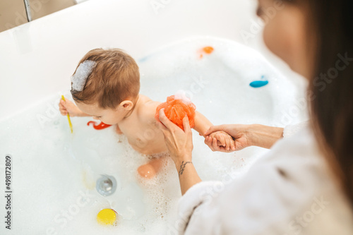 Tela Woman washing her child seated in the bath