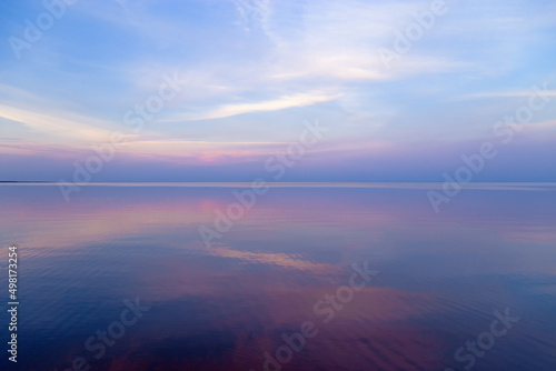 Sky background on sunset, colorful clouds. Nature abstract composition with reflections on sea water. Nature environment.