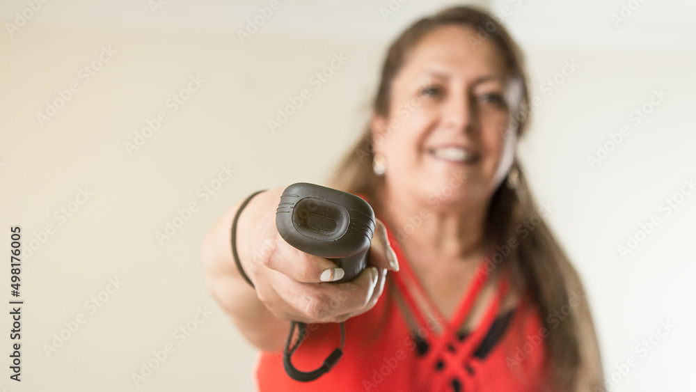 Fototapeta premium Latin mature woman playing with wireless controller