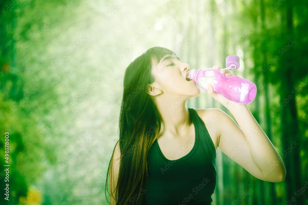 Young woman drinking water after exercise at park Young woman drinking water after exercise at park