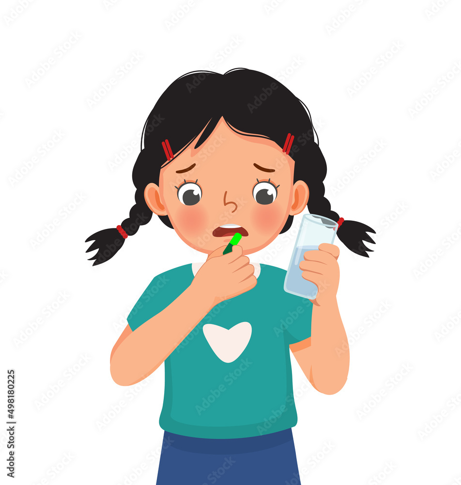 cute little girl taking a medicine capsule with a glass of water cute little girl taking a medicine capsule with a glass of water