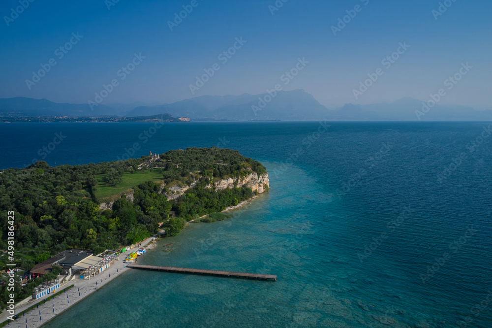 Panoramic aerial view of Lido delle Bionde beach.  Sirmione Archaeological site of Grotte di Catullo, Sirmione, Italy early morning aerial view. lake garda.