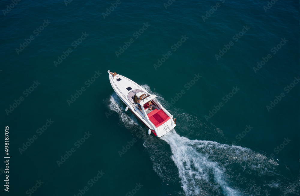 People rest on a boat. Drone view of a moving white boat on the water. Speedboat moves fast on the water top view. Speed boat with red seats aerial view. People rest on a boat. Drone view of a moving white boat on the water. Speedboat moves fast on the water top view. Speed boat with red seats aerial view.