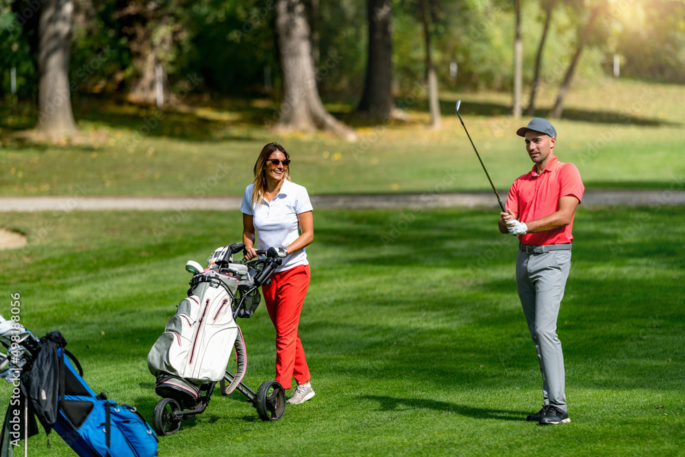 Young couple playing golf on a beautiful summer day Young couple playing golf on a beautiful summer day