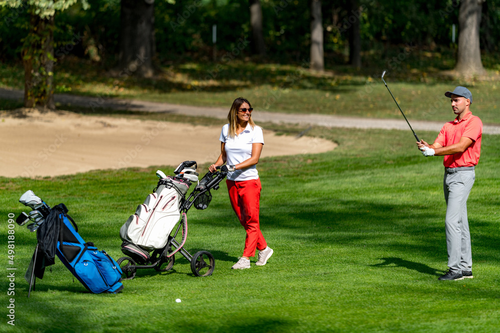 Young couple playing golf on a beautiful summer day