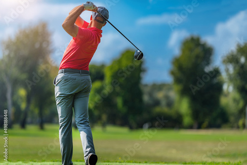Pro golfer in a golf swing, using a driver golf club, rear view