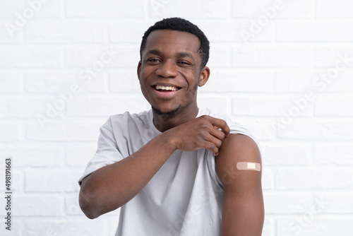 фотографія vaccinated African American man showing arm with medical plaster patch Plaster On Shoulder, black female after getting vaccine dose against covid