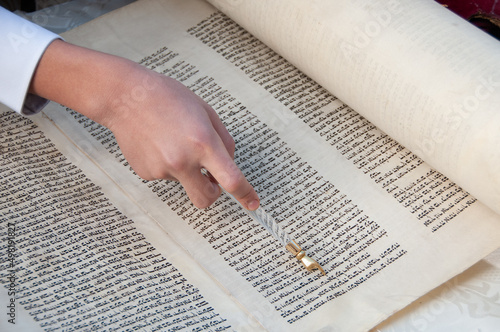 Fotografia, Obraz Reading the Torah, the five holy books of Moses and Judaism with the assistance of a pointer or yad to guide the reader through the Hebrew text