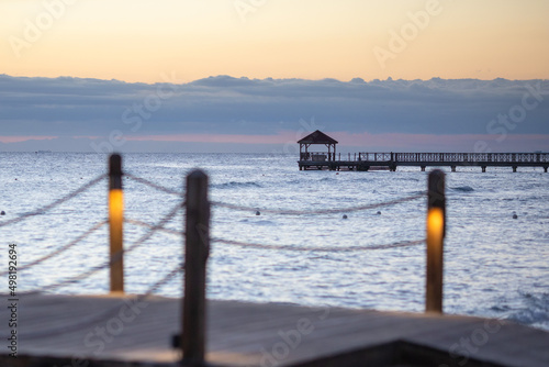 Sunset on the Caribbean coast in the Dominican Republic.Tourism,travel,recreation,background.Beautiful landscape of the sea coast.Wooden poles and rope railings of the pier, lights included close-up