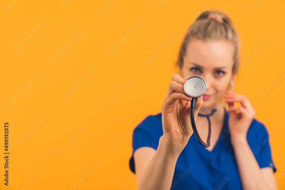 Fototapeta premium let's listen to your lungs - blonde nurse with stethoscope medium closeup studio shot orange background medical concept . High quality photo