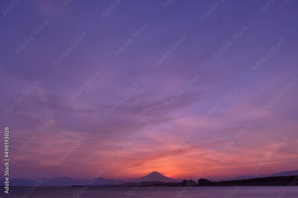 静かな海と富士山の裏に沈む太陽