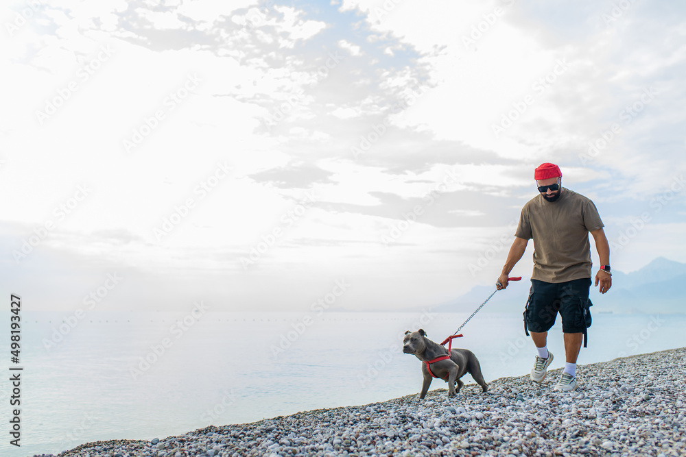 handsom man in red hat and sunglasses training dog outdoors in sity park zone dog walking area background