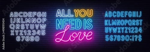 All you need is love neon lettering on brick wall background.