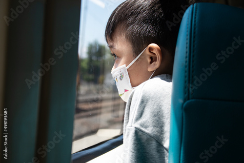 little boy looking in the mirror, straight hair and face mask on an out of focus background