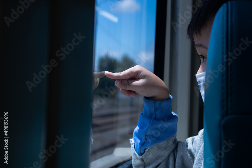 little boy pointing at the mirror, gray shirt, blue sleeves, defocused background

