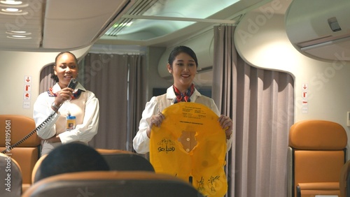 Fotografía Asian stewardess safety explaining passengers prior to flight take off in airpla