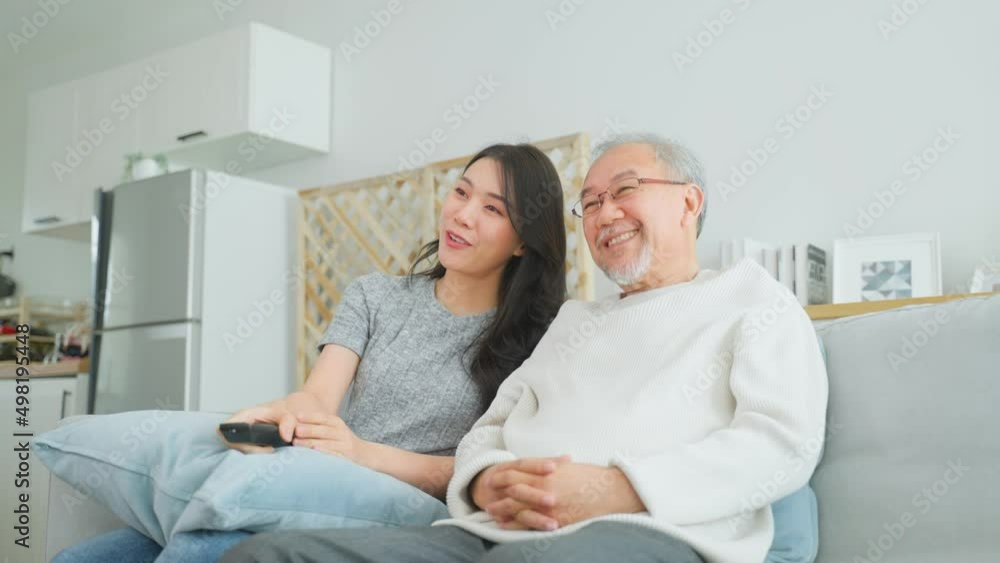 Asian senior father and daughter watch funny movie together at home. Asian senior father and daughter watch funny movie together at home.