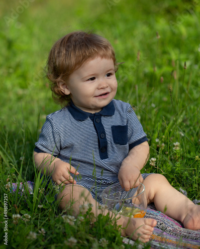 Little child play in park. Portrait of a happy baby in grass field.