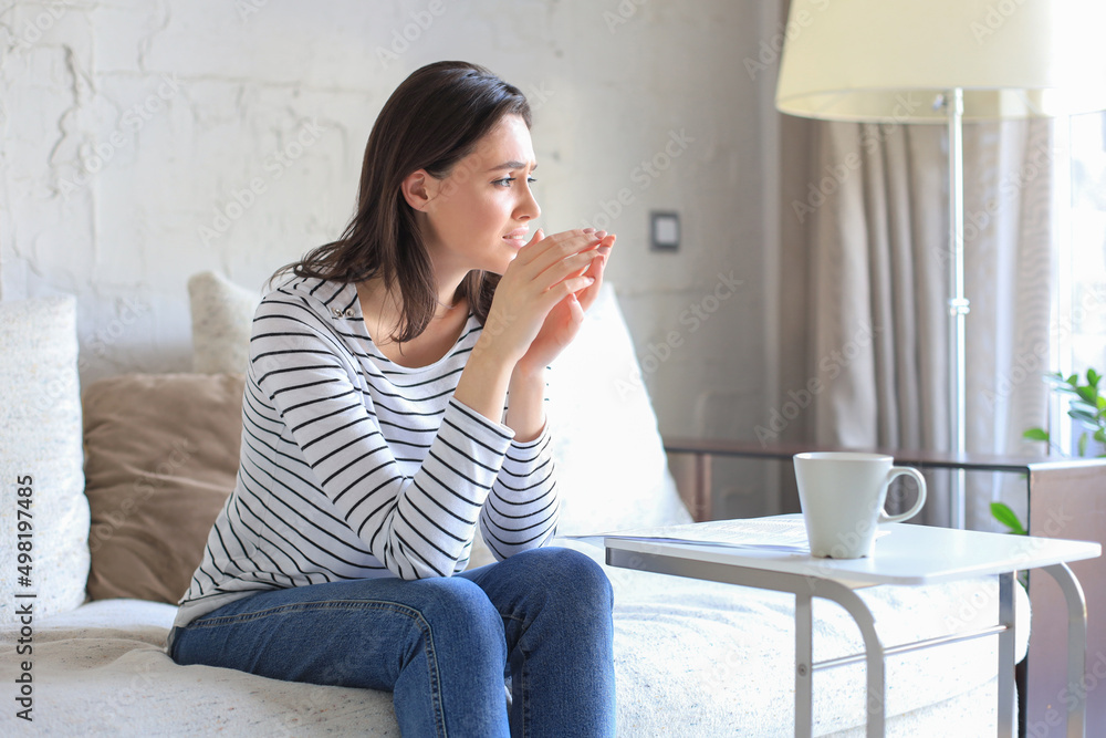 Sad woman with the bills sitting on a sofa in the living room. Sad woman with the bills sitting on a sofa in the living room.