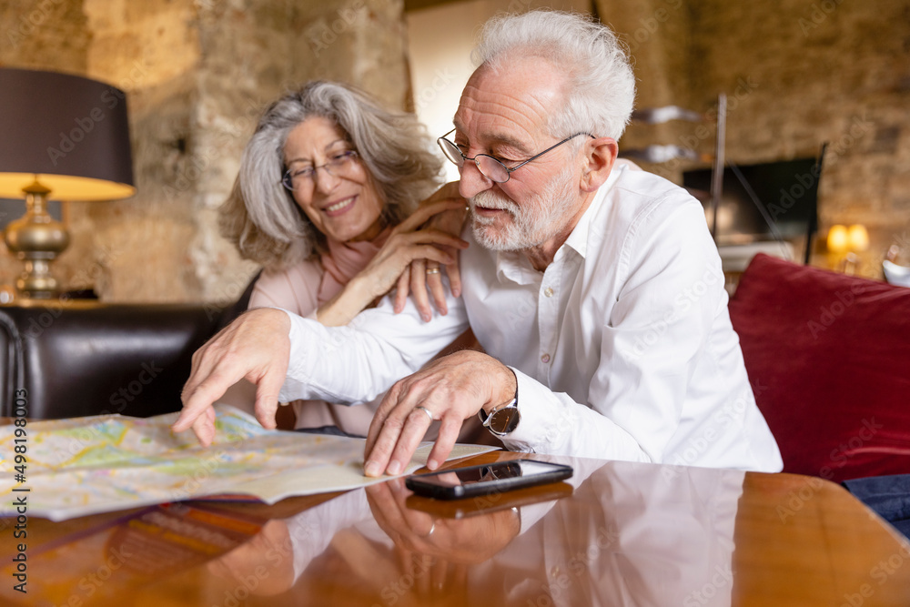 © Westend61 - Smiling senior man pointing at map sitting by woman on sofa at boutique hotel © Westend61 - Smiling senior man pointing at map sitting by woman on sofa at boutique hotel