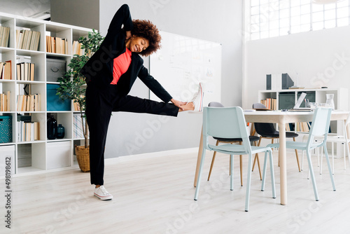 Businesswoman doing stretching exercise at desk in office photo