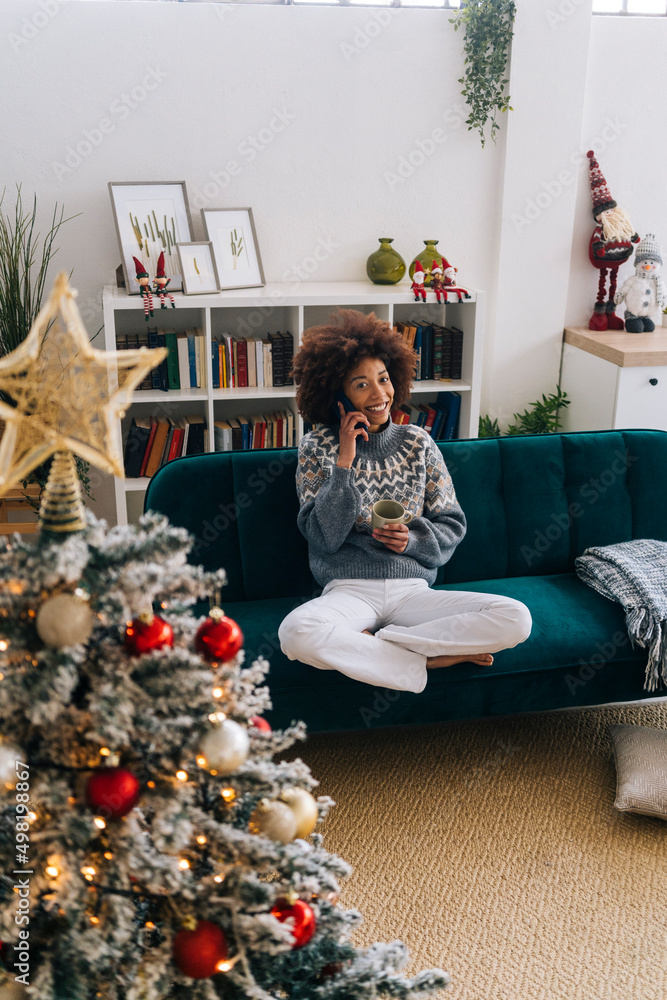 Happy woman talking on mobile phone sitting on sofa in living room Happy woman talking on mobile phone sitting on sofa in living room