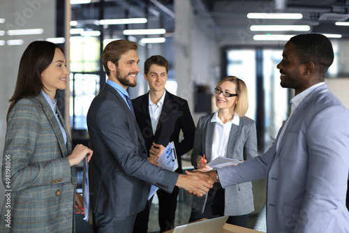 Confident business people shaking hands at workplace.