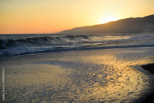 Landscape of sea and tropical beach at sunset or sunrise time for leisure travel and vacation. Reflection of sun in the water and sand on beach.