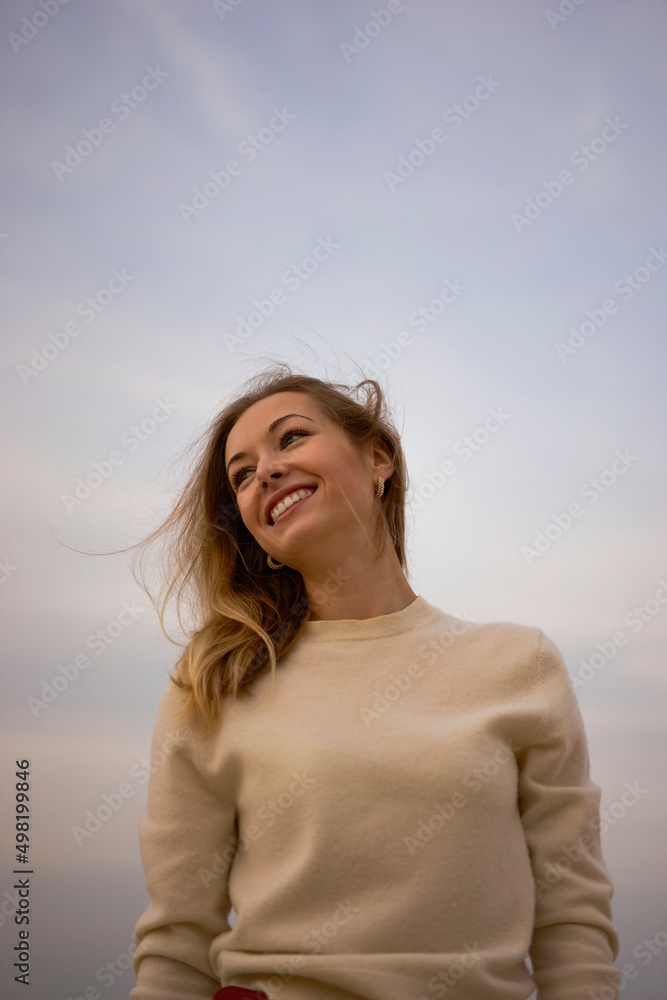 Happy beautiful woman standing in front of sky at sunset Happy beautiful woman standing in front of sky at sunset