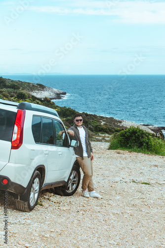 man lean on suv car enjoying view of the sea. summer road trip vacation