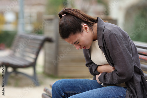 Teenage female suffering belly ache in a park