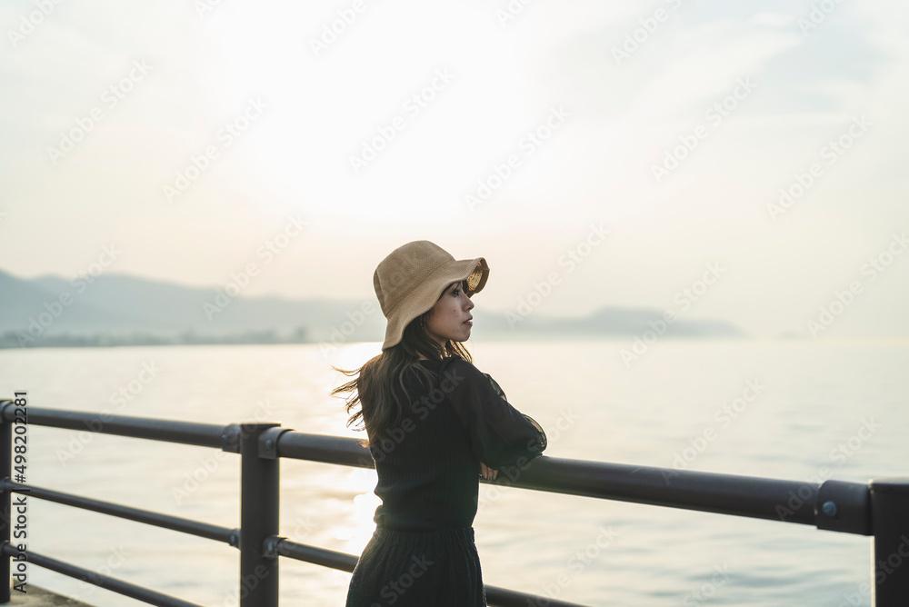 夕暮れの海で黄昏れる女性