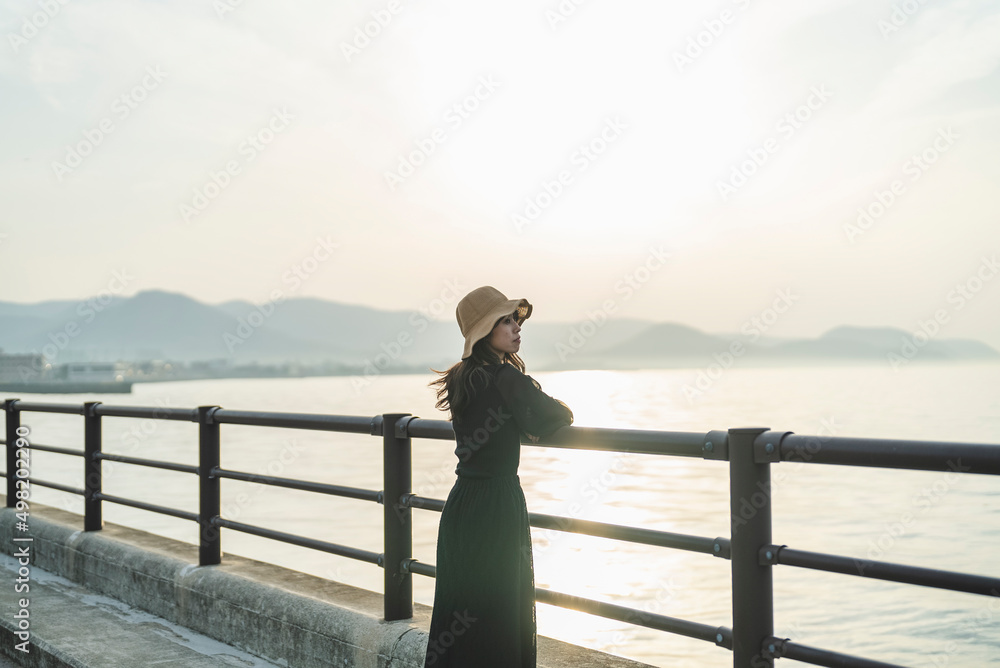 Fototapeta premium 夕暮れの海で黄昏れる女性
