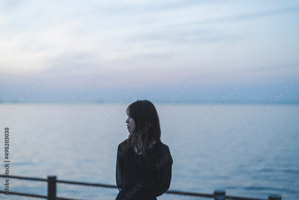 夕暮れの海沿いで散策する女性 夕暮れの海沿いで散策する女性