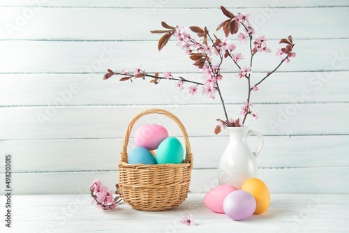 Canvas Print Easter eggs in a basket and pink cherry blossoms, Easter greeting card, wooden b