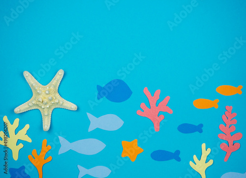 Starfish with seashells and fish made of paper on a blue background. Recreation Concept