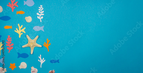 Starfish with seashells and fish made of paper on a blue background. Recreation Concept