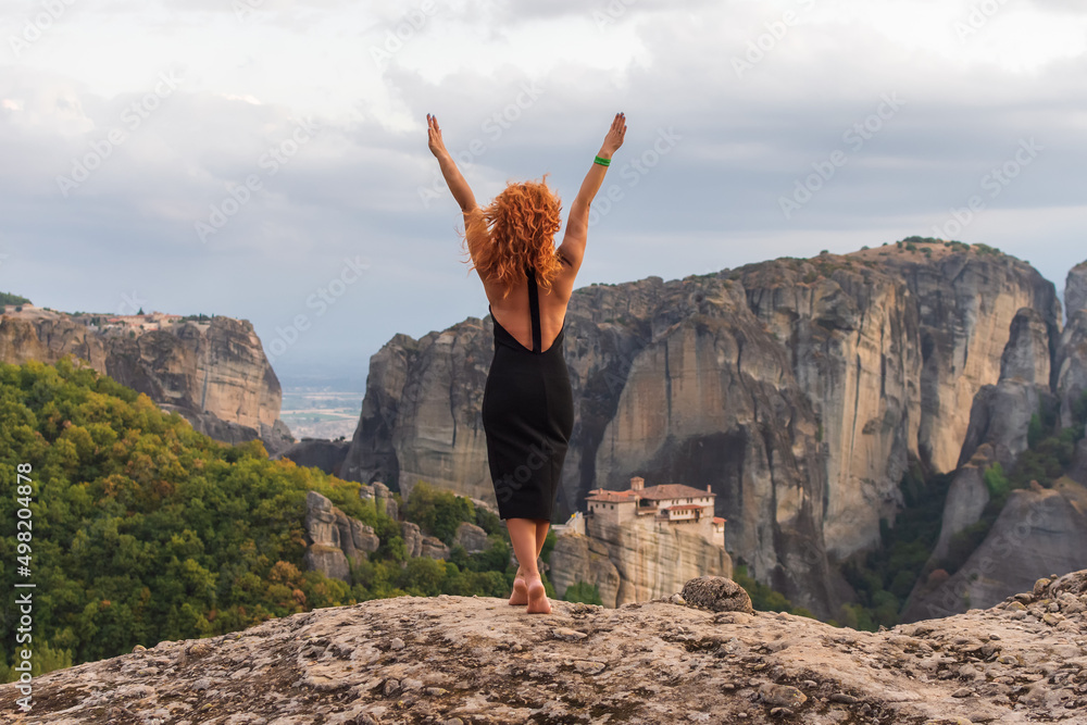 Young woman in black dress enjoying nature on the mountains near Meteora monasteries in Greece. Young woman in black dress enjoying nature on the mountains near Meteora monasteries in Greece.