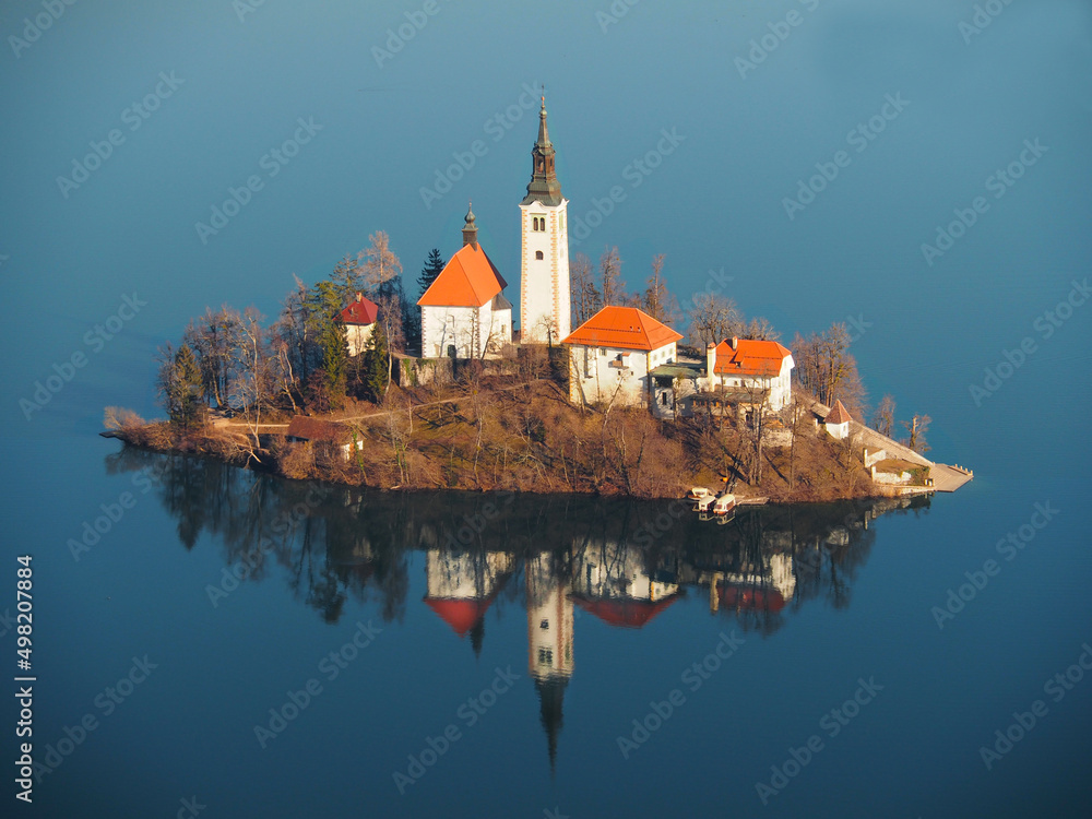 Church on an island in the middle of a lake. Small island with a church reflected in the water