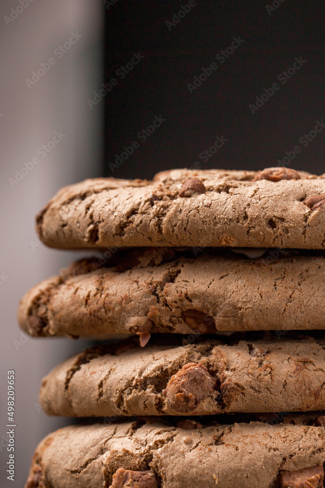 brown chocolate chip cookie large poan. On a black background. Chocolate chip cookies with brown chocolate chips are placed on a wooden table. brown chocolate chip cookie large poan. On a black background. Chocolate chip cookies with brown chocolate chips are placed on a wooden table.