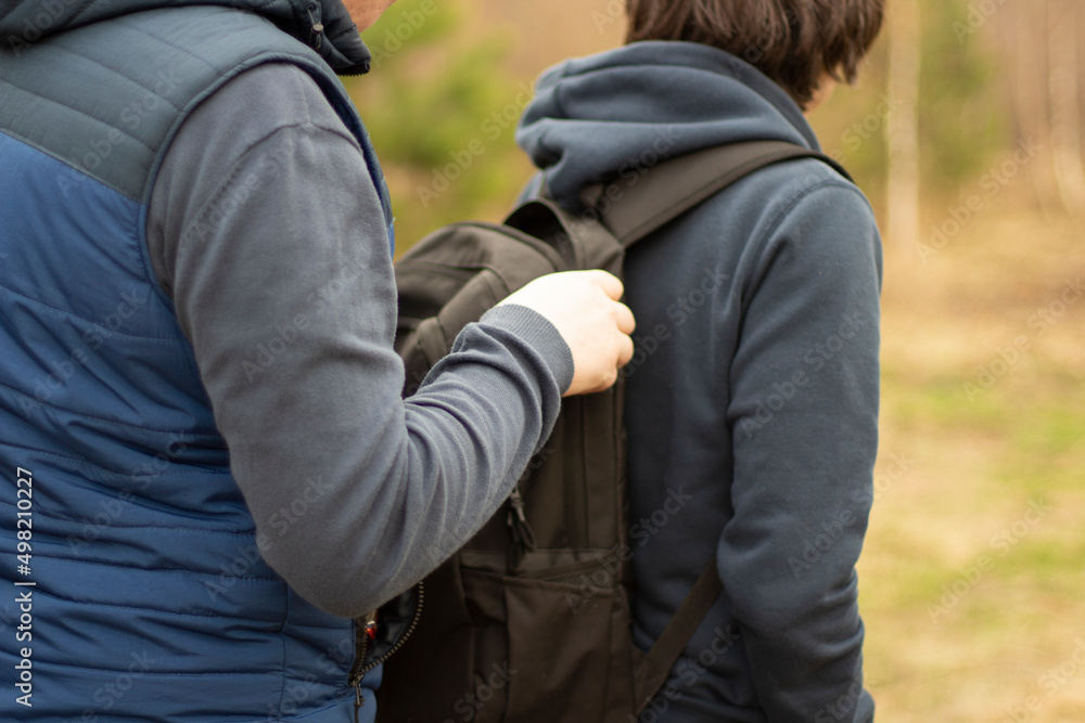 The guy is in a backpack. A man takes things from a friend's bag. The guy is in a backpack. A man takes things from a friend's bag.