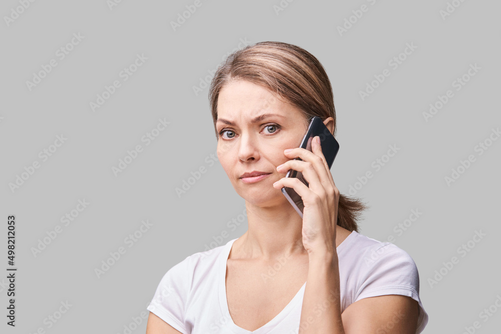 Pretty female portrait. Woman talking by mobile phone. Cute conversation concept. Commuter device. People emotion. Shoked face. Grey background. Copyspace. White t-shirt Pretty female portrait. Woman talking by mobile phone. Cute conversation concept. Commuter device. People emotion. Shoked face. Grey background. Copyspace. White t-shirt