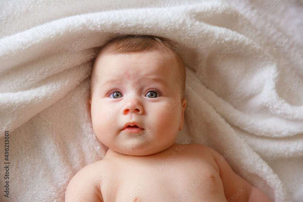 baby is wearing diapers and a white towel in bedroom. A newborn baby is