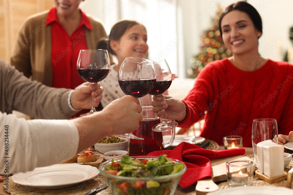 Family clinking glasses of wine at festive dinner, focus on hands. Christmas celebration