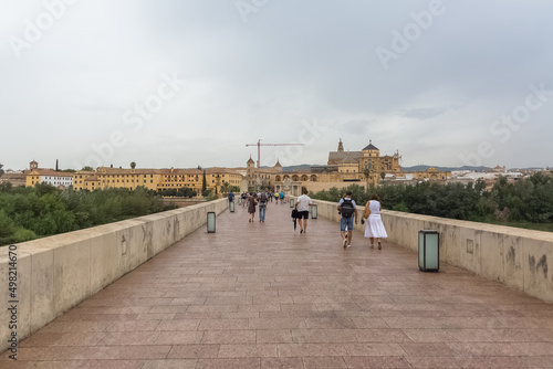 View at the Roman Bridge over Guadalquivir river, Mosque-Cathedral of Córdoba, Plaza del Triunfo as background, torurist people visiting, Cordoba downtown, Spain photo