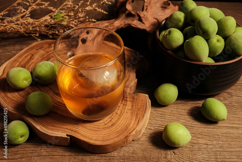 Homemade plum wine or UMESHU and green plums on wooden plate.