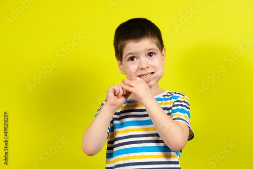 A little boy brushes his teeth with a toothbrush on a yellow background with place for text.